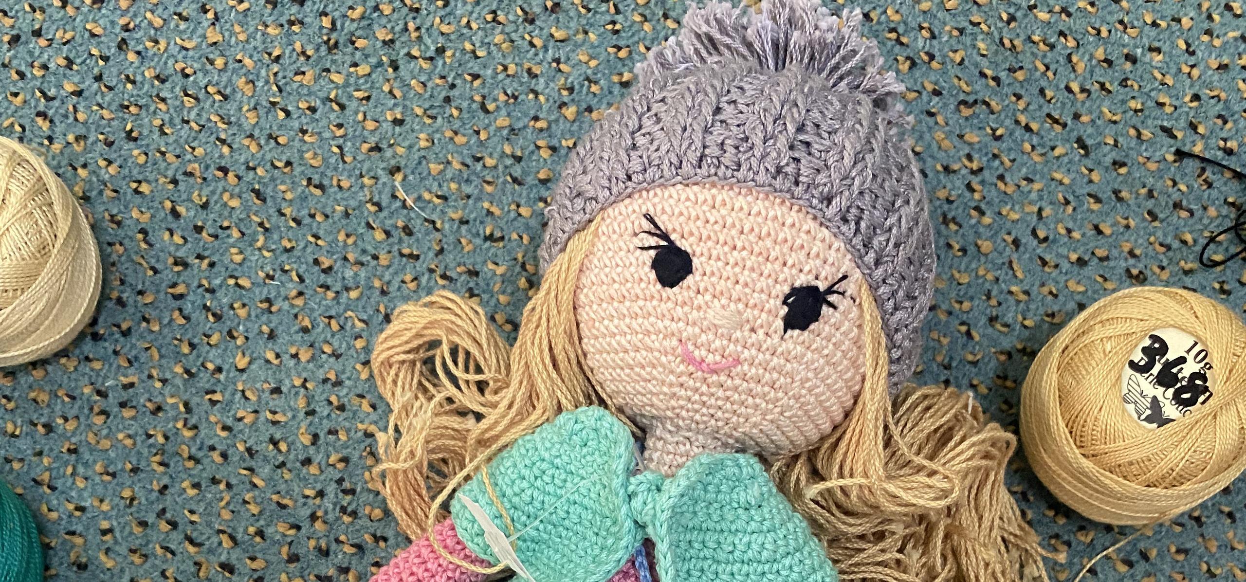 A crochet doll among spools of thread