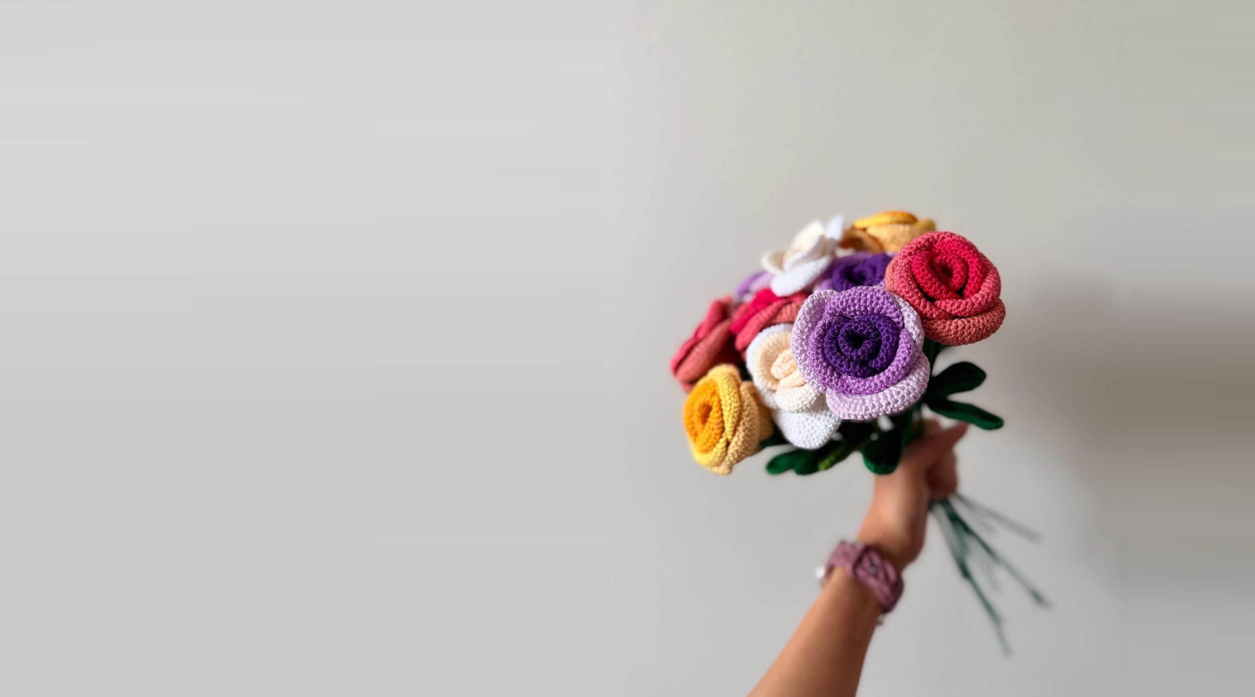 A hand holding a bouquet of crochet roses